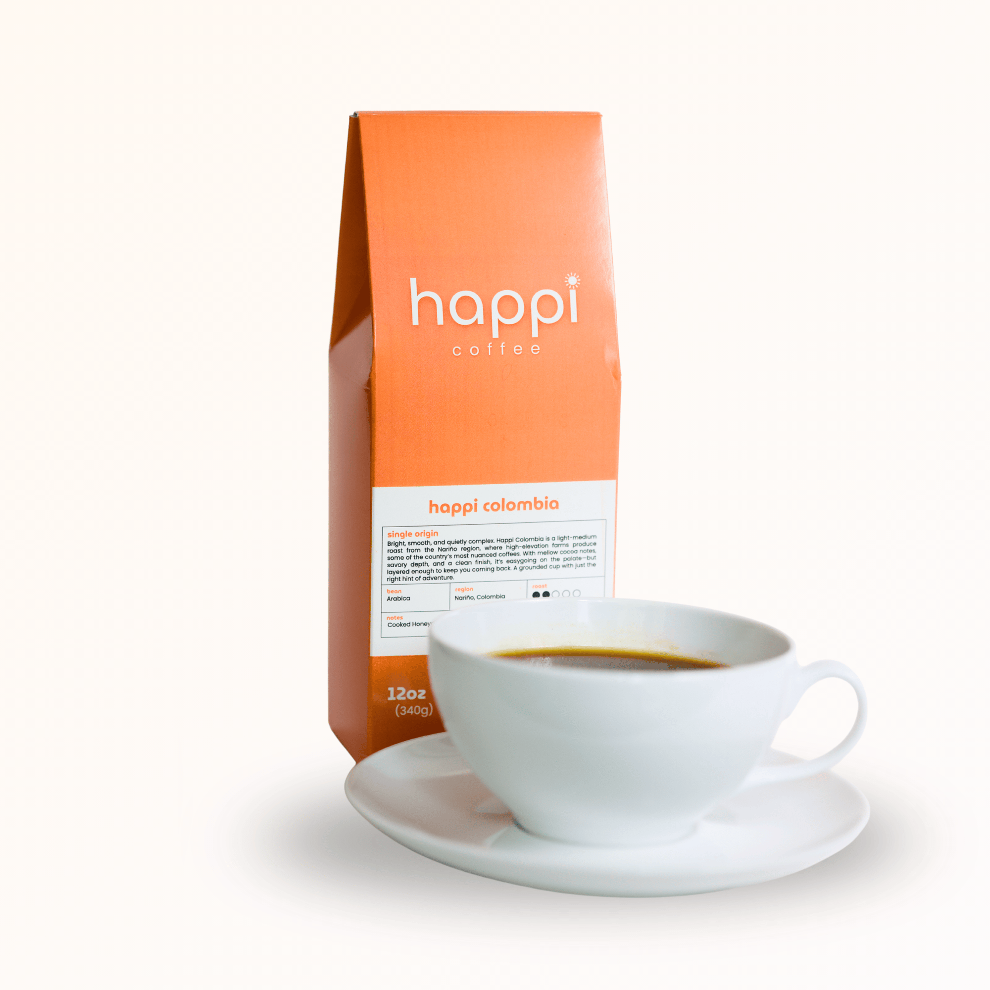 Side view of 12 oz bag of Happi Colombia with cup of coffee. Best Light Roast Coffee Beans with Bright Citrus, Cocoa Warmth & Smooth Body, Available Ground or Whole Bean
