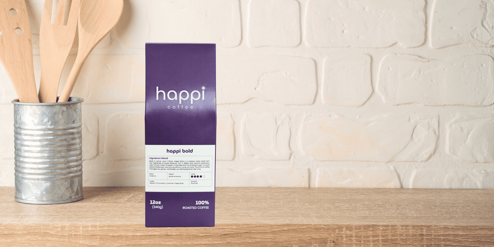 Happi Bold dark roast coffee bag on kitchen counter next to wooden utensils — specialty coffee with chocolate and caramel notes, roasted fresh and available ground or whole-bean.