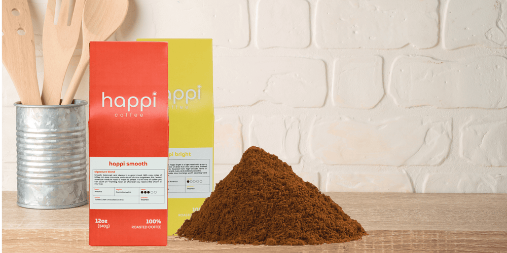 Fresh-roasted ground coffee next to Happi Smooth and Happi Bright bags on a kitchen counter
