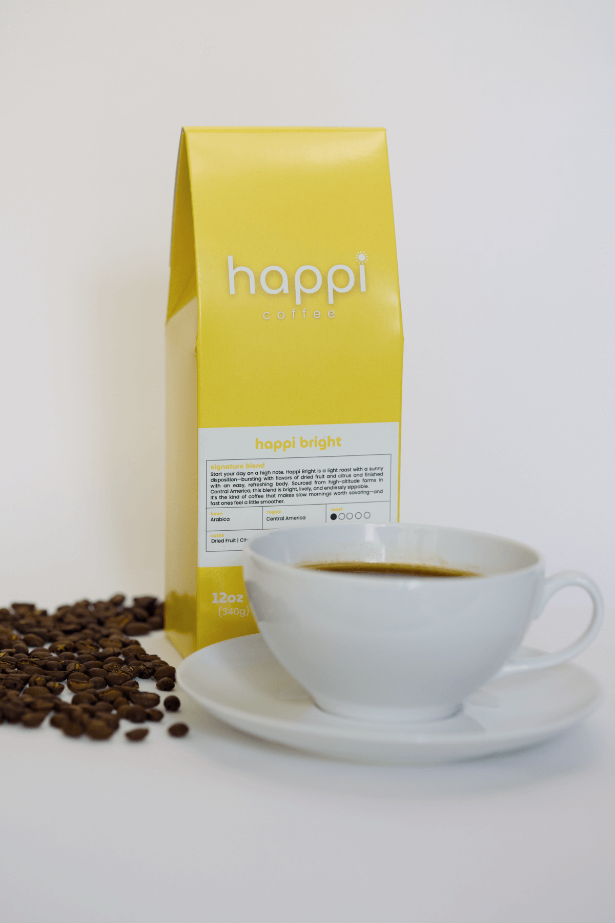 12 oz bag of Happi Bright light roast specialty coffee with scattered beans and brewed coffee in white cup