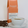 12 oz bag of happi colombia light roast specialty coffee with scattered beans and brewed coffee in white cup
