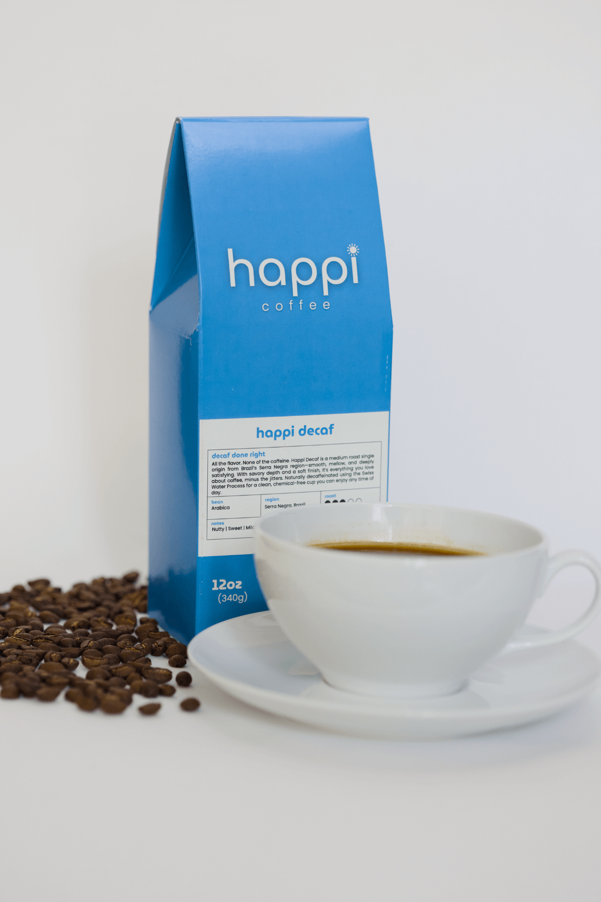12 oz bag of happi decaf medium roast specialty coffee with scattered beans and brewed coffee in white cup