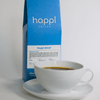 12 oz bag of happi decaf medium roast specialty coffee with brewed coffee in a white cup and saucer