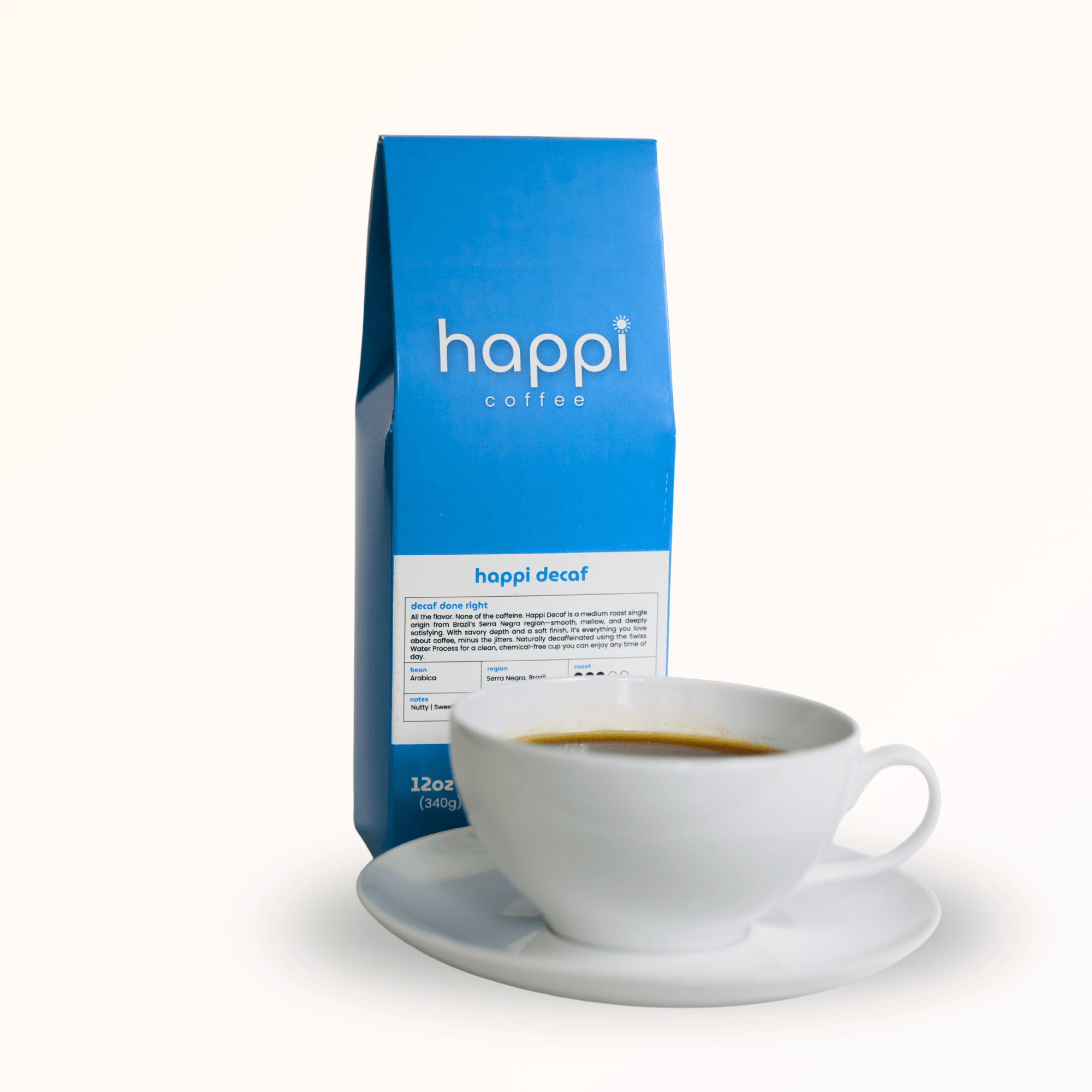 Side view of 12 oz bag of Happi Decaf next to a cup of coffee. Best decaf coffee beans with nutty sweetness & balanced flavor. Available Ground or Whole Bean