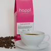 12 oz bag of happi guatemala light roast specialty coffee with scattered beans and brewed coffee in white cup