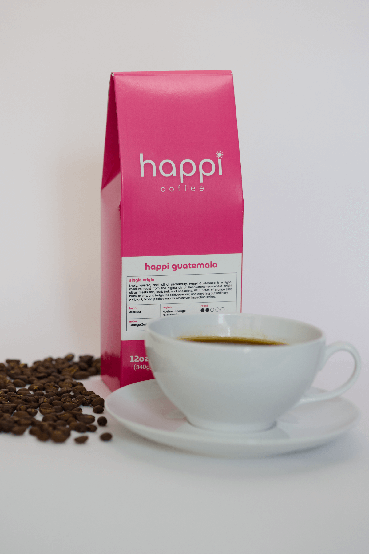 12 oz bag of happi guatemala light roast specialty coffee with scattered beans and brewed coffee in white cup