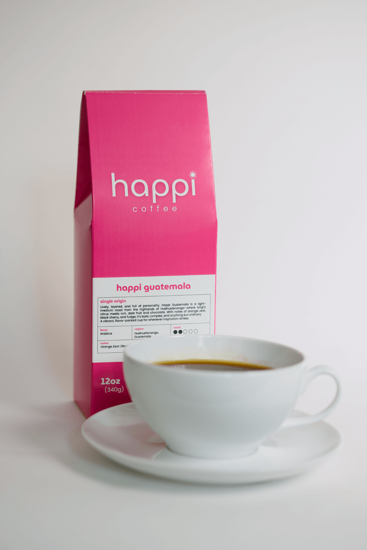12 oz bag of happi guatemala light roast specialty coffee with brewed coffee in a white cup and saucer