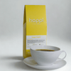 View of 12 oz bag of Happi Bright next to a cup of coffee. Best Light Roast Coffee Beans with Citrus & Floral Flavor, Available Ground or Whole Bean