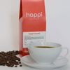 12 oz bag of Happi Smooth medium roast specialty coffee with scattered beans and brewed coffee in white cup